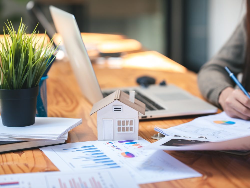 Close-up of hands reviewing real estate investment contracts and financial charts, symbolizing strategic property planning.